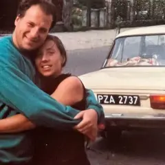 Piotr Gąsowski z partnerką przy starym samochodzie. Uśmiechnięci, przytuleni, w tle polskie tablice rejestracyjne.