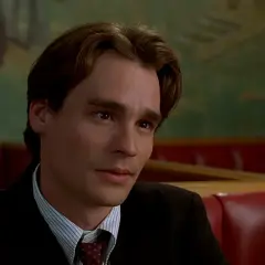 Robert Sean Leonard w garniturze, w tle zielona ściana z malowidłem. Jego filmy i seriale to klasyka.