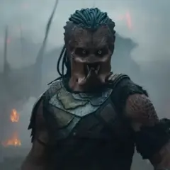 Predator w strefie zagrożenia, otoczony dymem i płomieniami. Jego groźna twarz i zbroja budzą strach.
