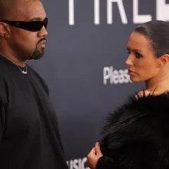 Kanye West i Bianca na ściance. Kanye w czarnym t-shircie i okularach, Bianca w futrzanym płaszczu.