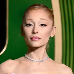 Ariana Grande w błyszczącym naszyjniku, wygląda na lekko zmęczoną, jakby zmagała się z jakąś chorobą.