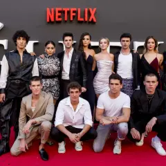 Cała obsada serialu "Szkoła dla elity" pozuje na czerwonym dywanie przed logo Netflix.
