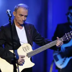 Seweryn Krajewski na scenie, grając na gitarze. W tle basista.