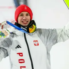 Kacper Tomasiak z medalem i nartami, dumny syn, który spełnia marzenia rodziców.
