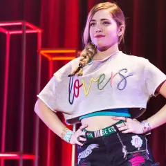 Młoda dziewczyna z warkoczem, w crop topie z napisem "lovers", pewnie pozuje na scenie. To część obsady "Go! Żyj po swojemu".