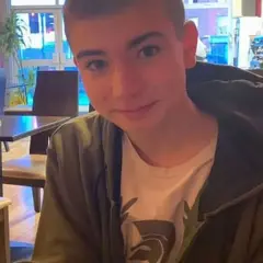 Młody mężczyzna, syn Sinead O'Connor, siedzi w kawiarni, ubrany w bluzę z kapturem.