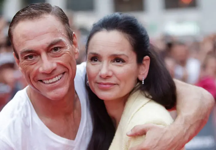Jean-Claude Van Damme z uśmiechem obejmuje swoją żonę.
