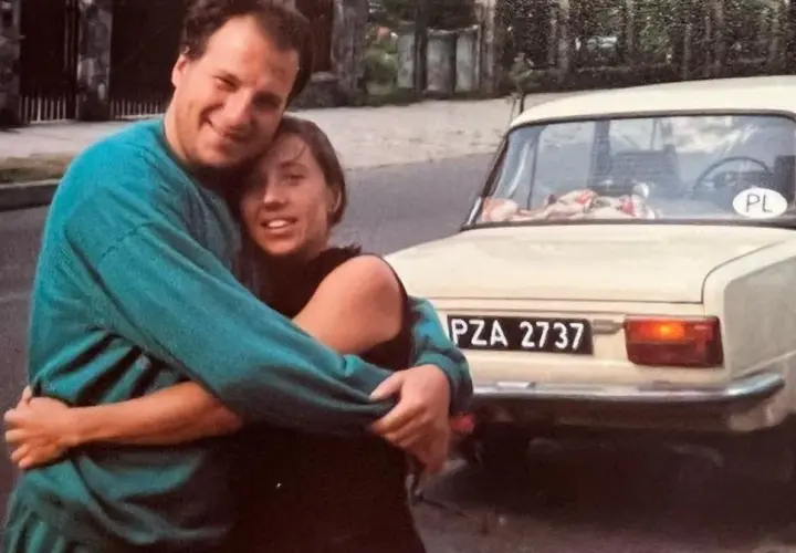 Piotr Gąsowski z partnerką przy starym samochodzie. Uśmiechnięci, przytuleni, w tle polskie tablice rejestracyjne.
