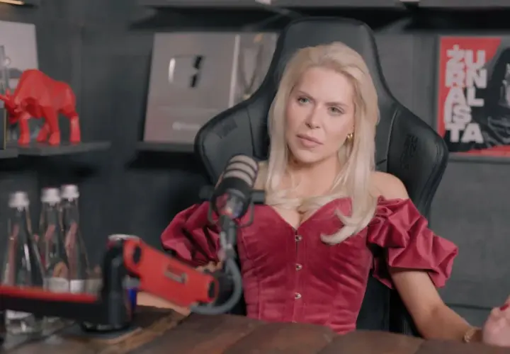 Blondynka w czerwonym gorsecie, przypominająca brata Julii von Stein, siedzi przed mikrofonem.