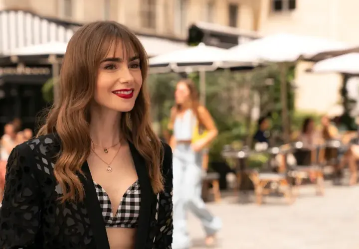 Emily w Paryżu, uśmiechnięta, w stylowej stylizacji, na tle paryskiej kawiarni.