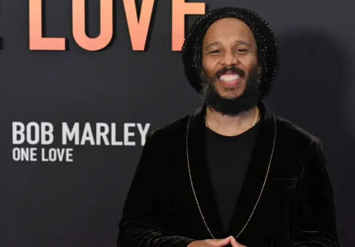 Uśmiechnięty Ziggy Marley na tle napisu "Bob Marley: One Love". Wiele dzieci Boba Marleya kontynuuje jego dziedzictwo.
