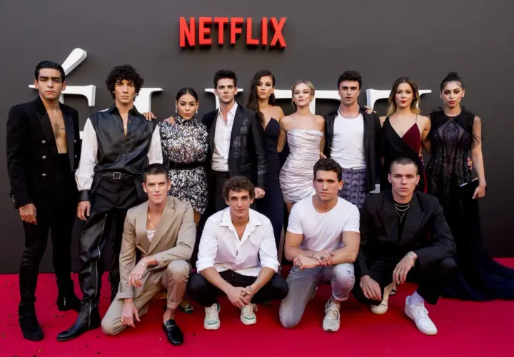 Cała obsada serialu "Szkoła dla elity" pozuje na czerwonym dywanie przed logo Netflix.