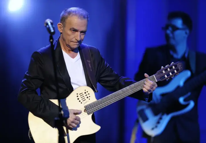 Seweryn Krajewski na scenie, grając na gitarze. W tle basista.