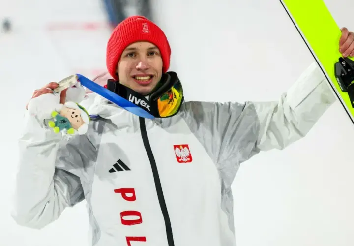 Kacper Tomasiak z medalem i nartami, dumny syn, który spełnia marzenia rodziców.