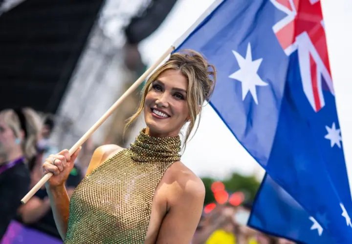 Uśmiechnięta kobieta z flagą Australii, dumna reprezentacja kraju na Eurowizji.
