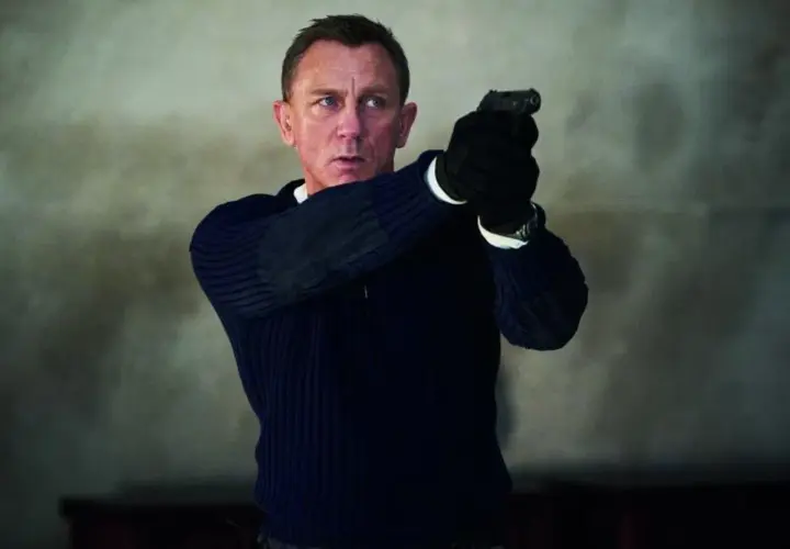 Daniel Craig w roli Jamesa Bonda, gotów do akcji z pistoletem w dłoni. Scena jak z najlepszych filmów o Jamesie Bondzie.