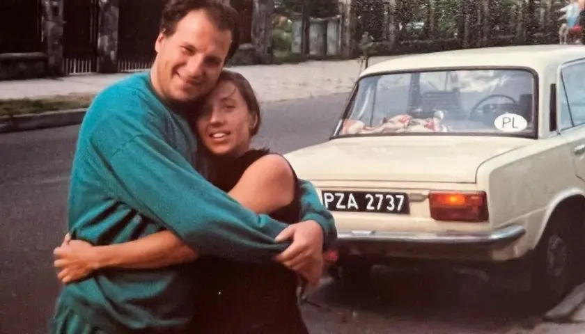 Piotr Gąsowski z partnerką przy starym samochodzie. Uśmiechnięci, przytuleni, w tle polskie tablice rejestracyjne.