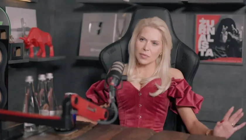 Blondynka w czerwonym gorsecie, przypominająca brata Julii von Stein, siedzi przed mikrofonem.