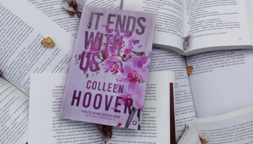 Książka "It Ends With Us" Colleen Hoover na tle innych otwartych książek.