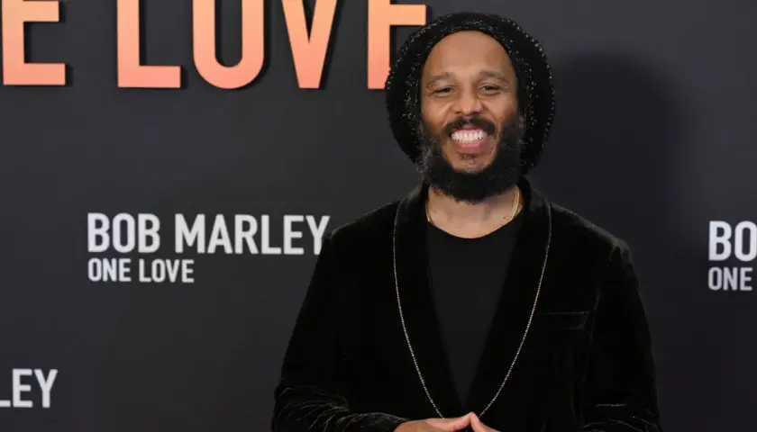 Uśmiechnięty Ziggy Marley na tle napisu "Bob Marley: One Love". Wiele dzieci Boba Marleya kontynuuje jego dziedzictwo.