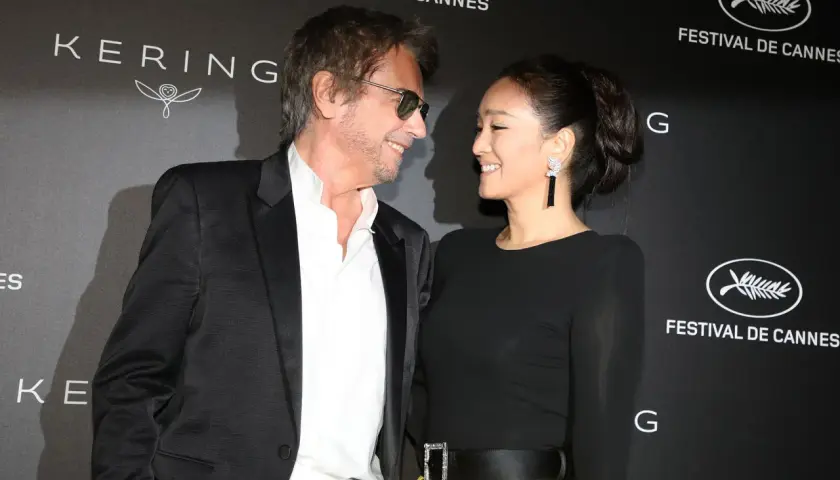 Jean-Michel Jarre i jego żona, Gong Li, uśmiechają się do siebie na tle napisu "Festival de Cannes".