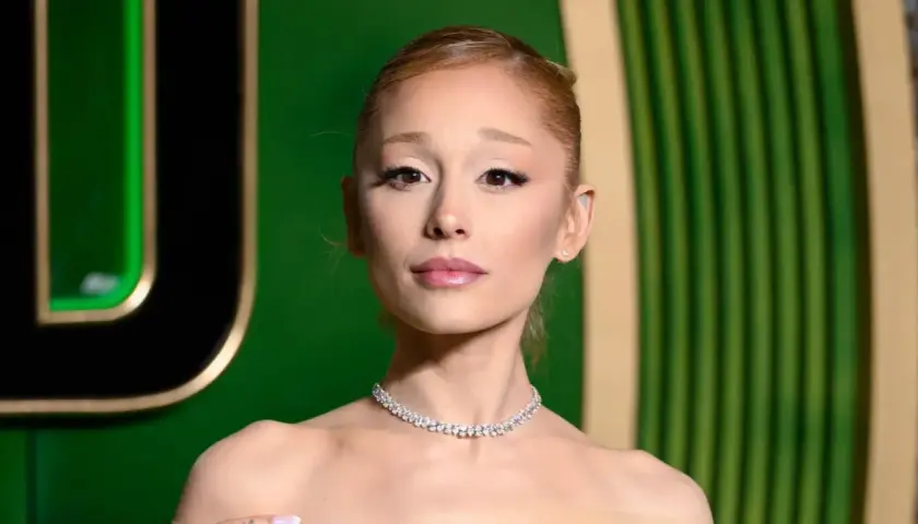 Ariana Grande w błyszczącym naszyjniku, wygląda na lekko zmęczoną, jakby zmagała się z jakąś chorobą.