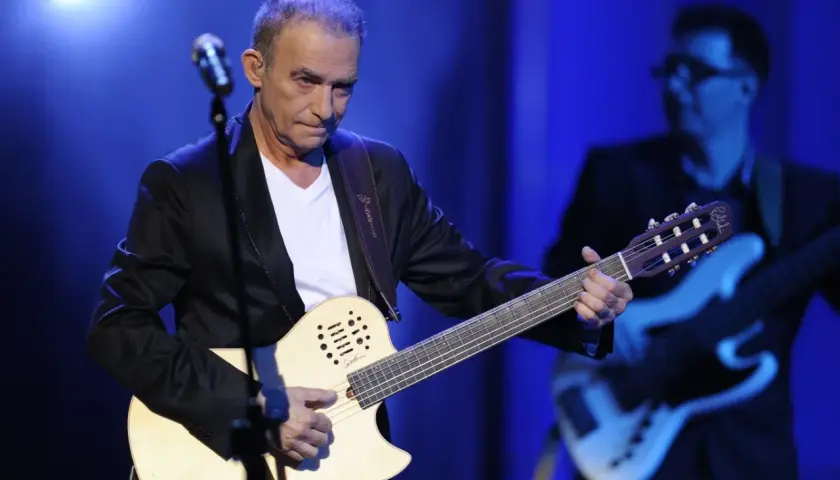Seweryn Krajewski na scenie, grając na gitarze. W tle basista.