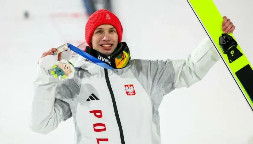 Kacper Tomasiak z medalem i nartami, dumny syn, który spełnia marzenia rodziców.