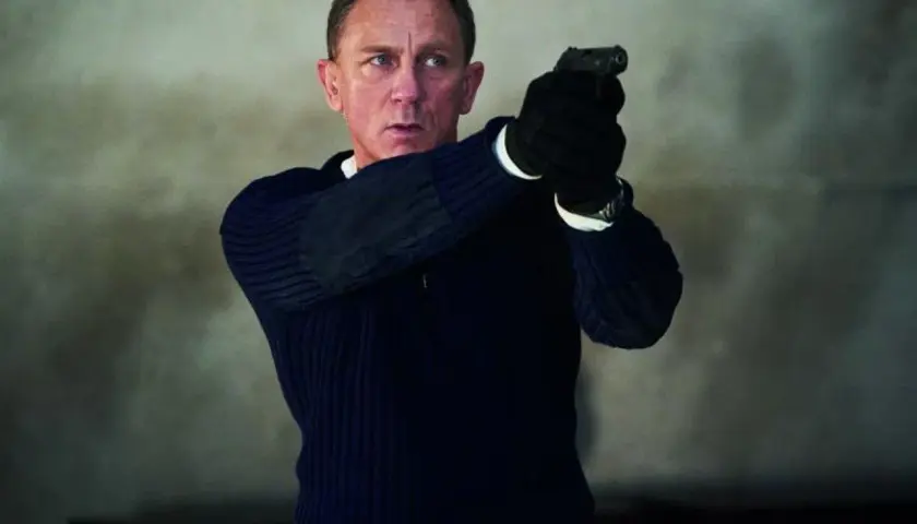 Daniel Craig w roli Jamesa Bonda, gotów do akcji z pistoletem w dłoni. Scena jak z najlepszych filmów o Jamesie Bondzie.