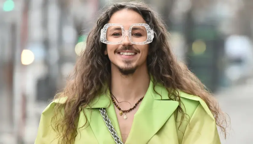 Uśmiechnięty Michał Szpak w limonkowym żakiecie i transparentnych okularach. Czy Michał Szpak jest gejem? To pytanie nurtuje wielu, ale jego styl i pewność siebie mówią same za siebie.