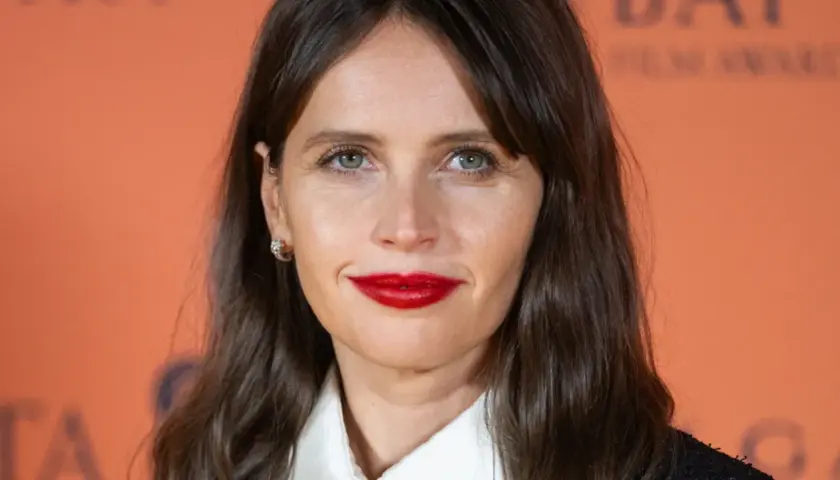Felicity Jones, znana z wielu filmów, z uśmiechem i wyrazistą szminką na ustach.