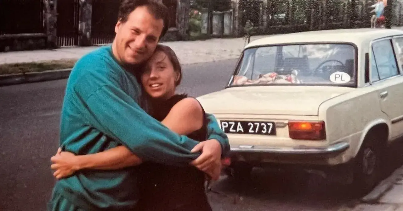 Piotr Gąsowski z partnerką przy starym samochodzie. Uśmiechnięci, przytuleni, w tle polskie tablice rejestracyjne.