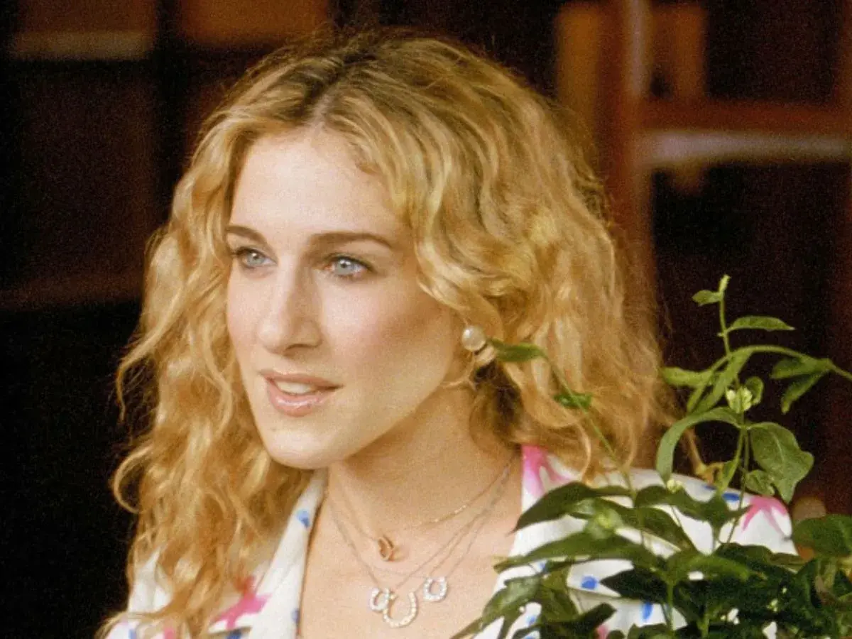 Sarah Jessica Parker w jednym ze swoich filmów, z burzą blond loków i delikatnym uśmiechem.