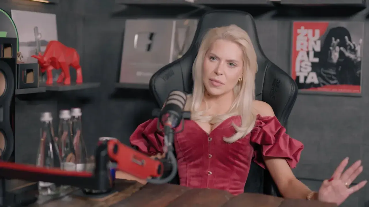 Blondynka w czerwonym gorsecie, przypominająca brata Julii von Stein, siedzi przed mikrofonem.