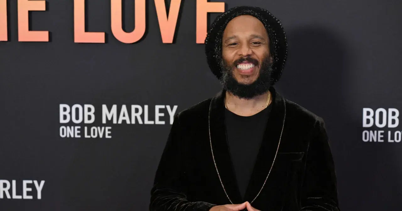 Uśmiechnięty Ziggy Marley na tle napisu "Bob Marley: One Love". Wiele dzieci Boba Marleya kontynuuje jego dziedzictwo.