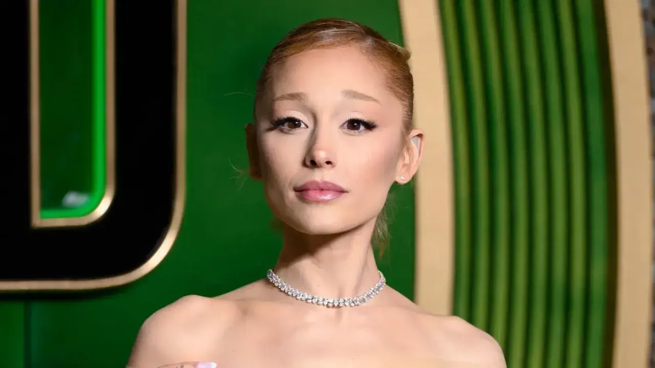 Ariana Grande w błyszczącym naszyjniku, wygląda na lekko zmęczoną, jakby zmagała się z jakąś chorobą.