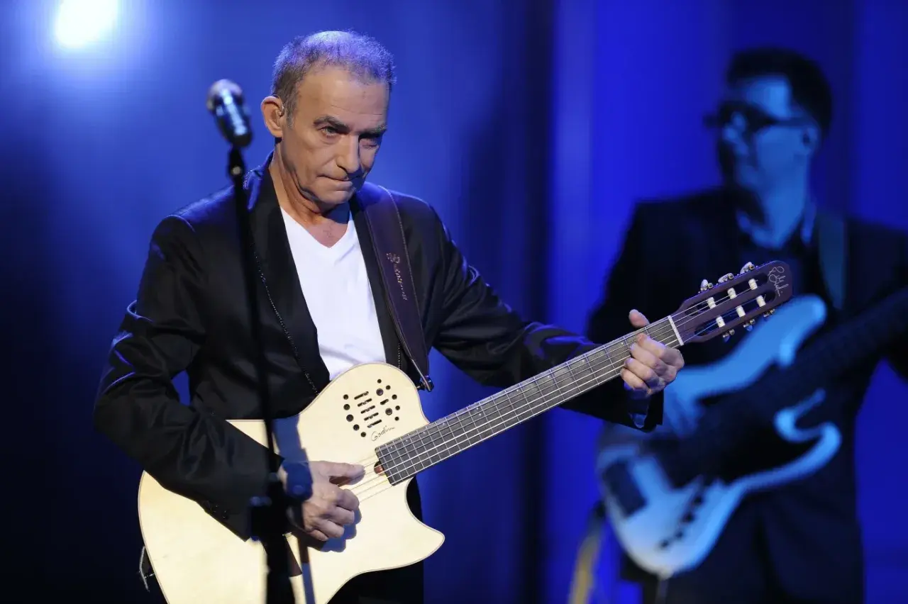 Seweryn Krajewski na scenie, grając na gitarze. W tle basista.