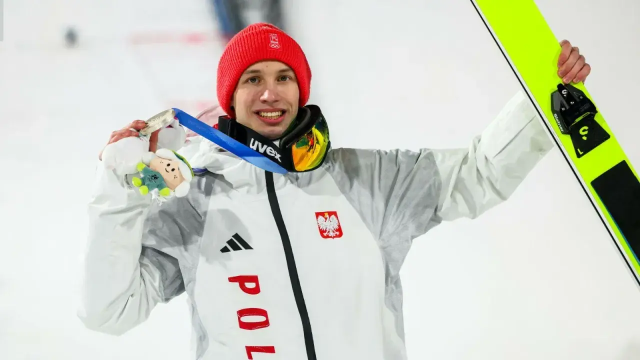 Kacper Tomasiak z medalem i nartami, dumny syn, który spełnia marzenia rodziców.