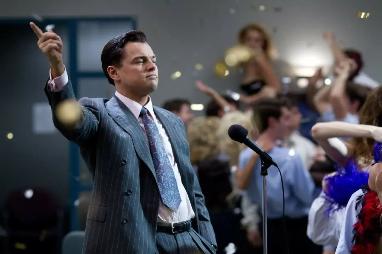 Jordan Belfort, znany jako wilk z Wall Street, przemawia do tłumu na imprezie, podczas gdy konfetti opada wokół.