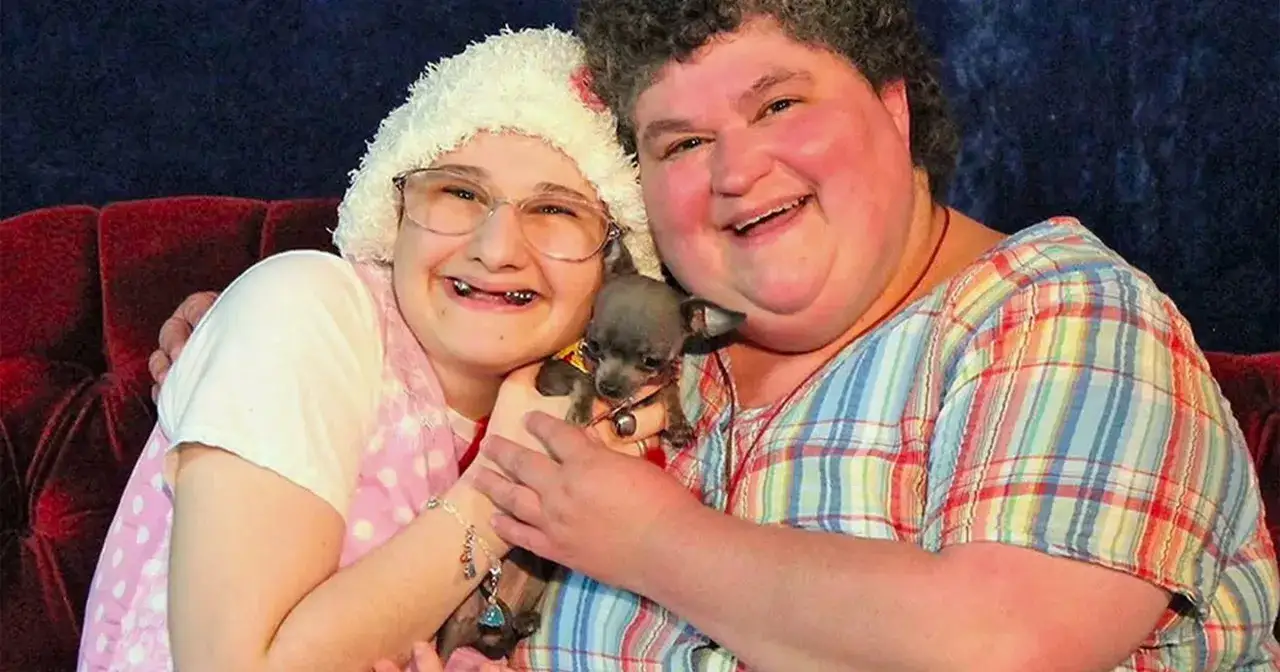 Gypsy Rose Blanchard z matką i małym pieskiem. Uśmiechnięte, siedzą na czerwonej kanapie.