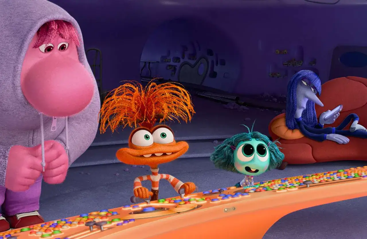 Nowe emocje w Inside Out 2: różowa postać w bluzie, pomarańczowy stworek i niebieska dziewczynka przy konsoli.