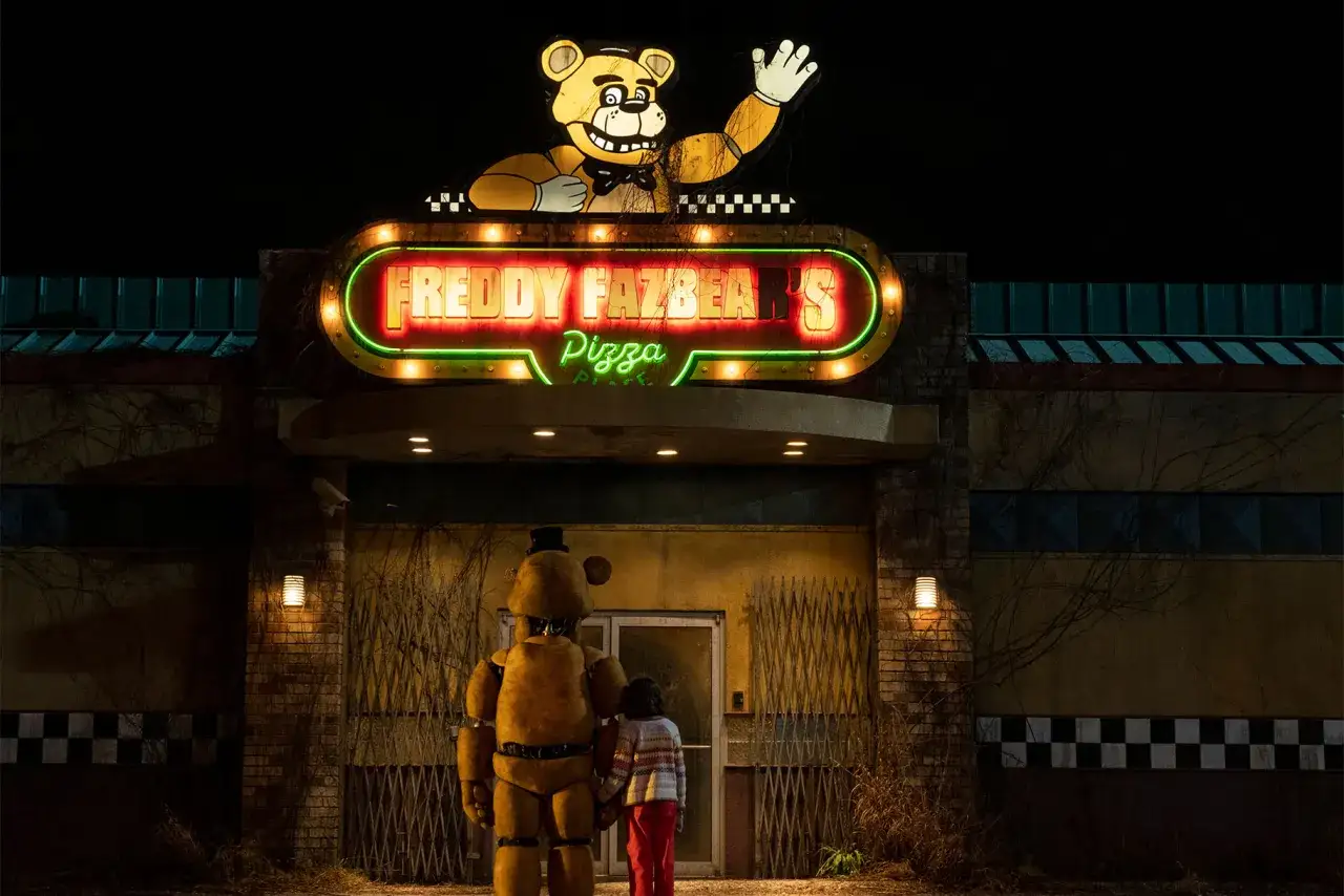Nocna wizyta przed Freddy Fazbear's Pizza. Dziecko i Freddy stoją przed neonowym szyldem, zapowiadając mroczne przygody w stylu fnaf movie 2.