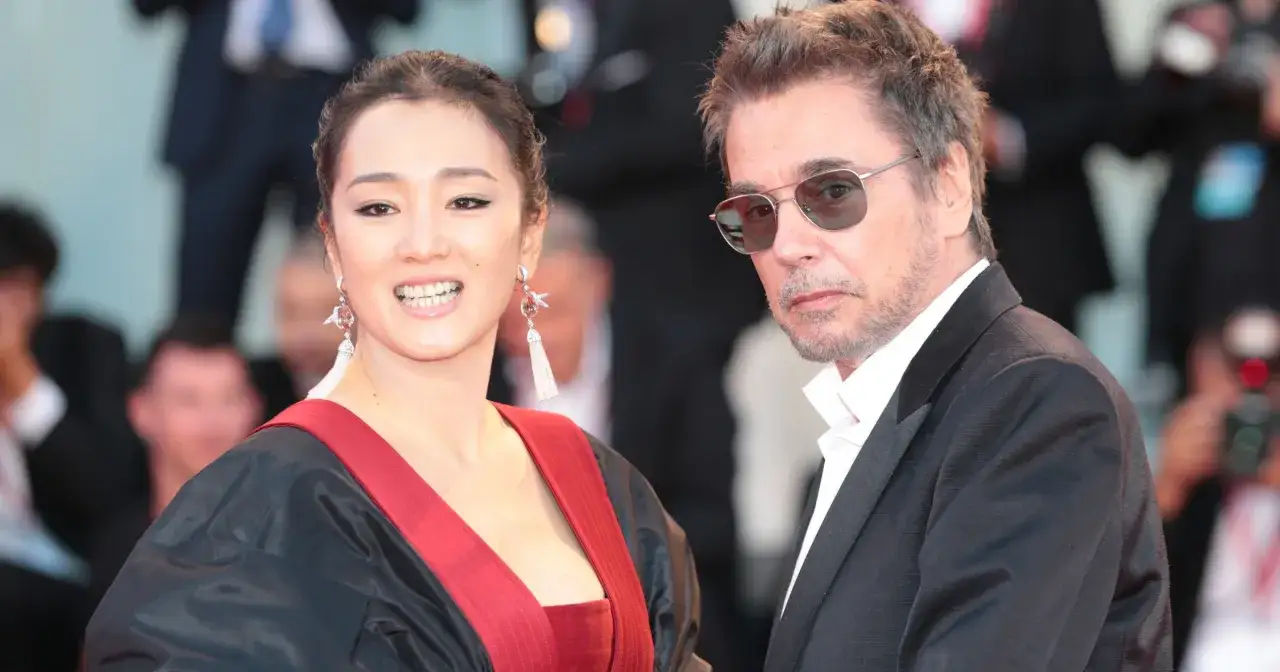Jean-Michel Jarre z żoną, Gong Li, na czerwonym dywanie. Ona w czarno-czerwonej kreacji, on w garniturze i okularach.