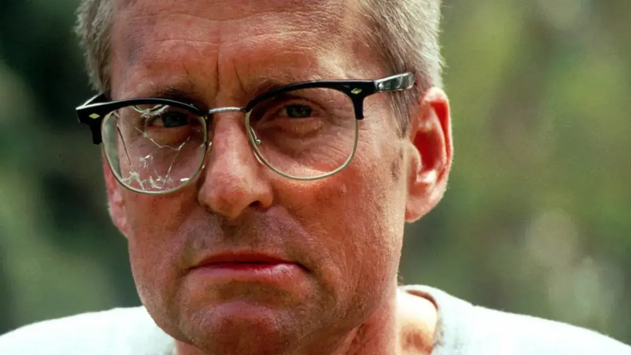 Michael Douglas w okularach z pękniętą szybką, w kadrze z jednego z jego filmów.