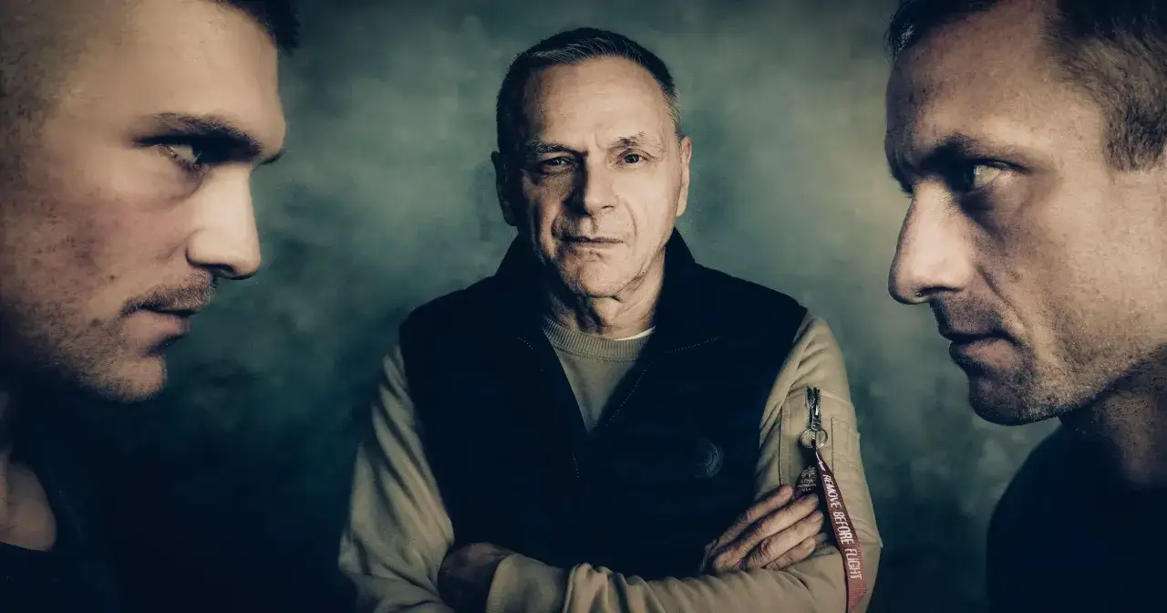 Trzech mężczyzn. Starszy patrzy prosto, dwaj młodsi z profilu, jakby mówili: 