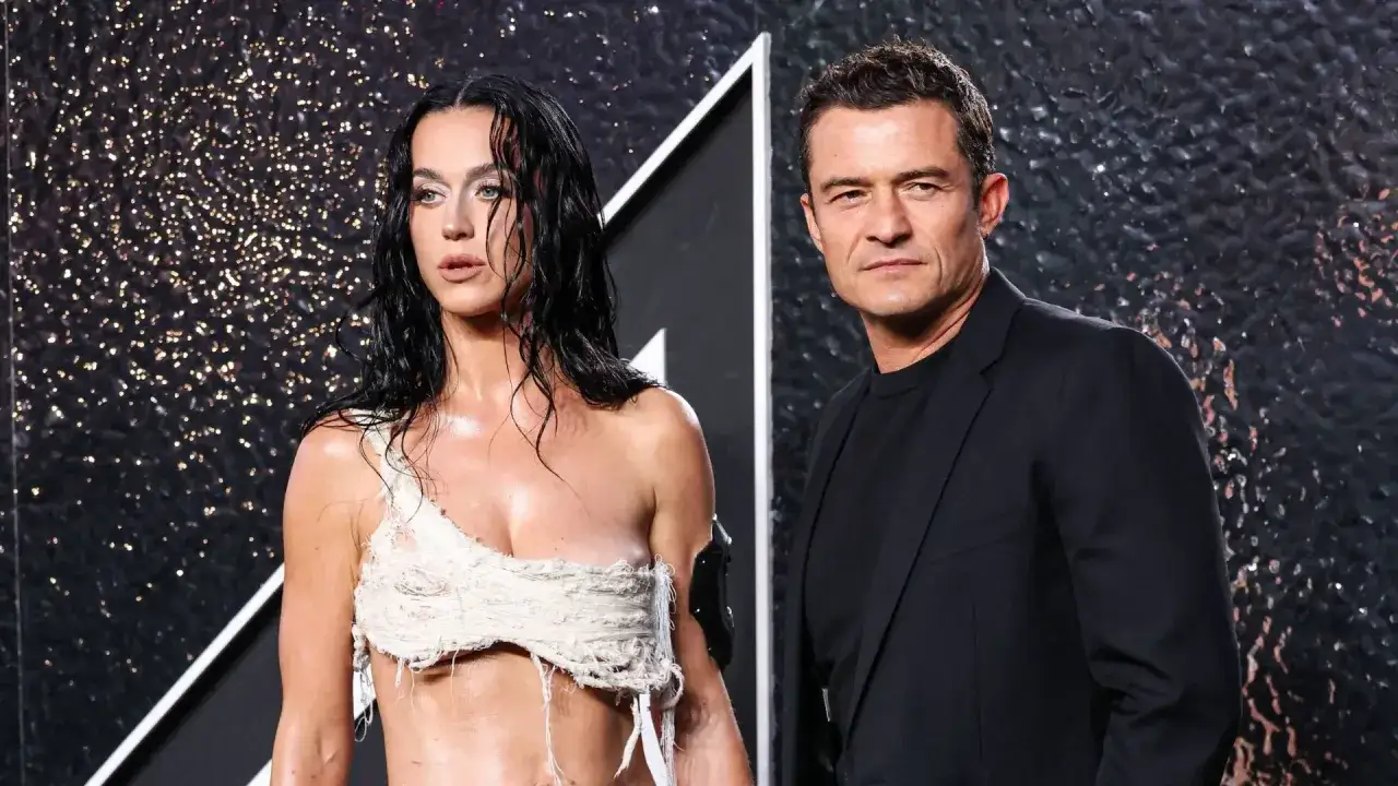 Katy Perry i Orlando Bloom na ściance. Ona w odważnej, postrzępionej kreacji, on w eleganckim czarnym garniturze.